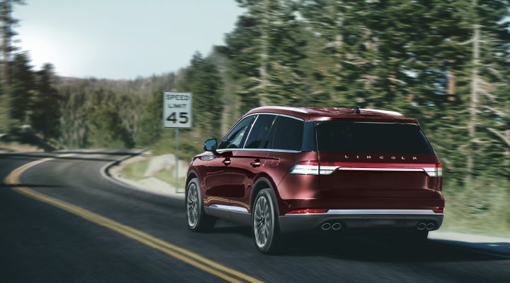 A 2024 Lincoln Aviator® SUV is being driven on a winding mountain road | Buss Lincoln in McHenry IL