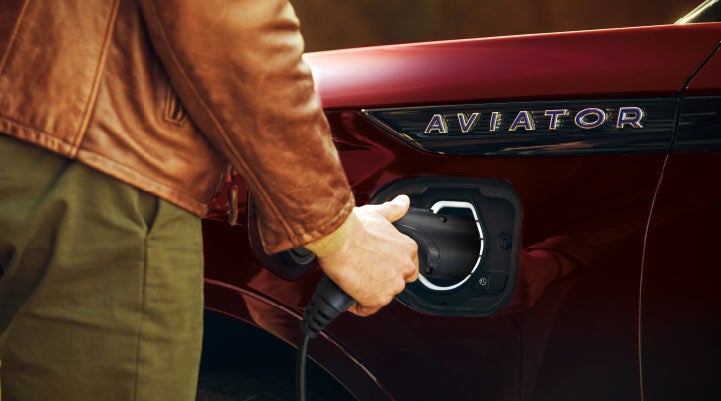 A hand is shown plugging in the charger into the charging port of a 2021 Lincoln Aviator | Buss Lincoln in McHenry IL
