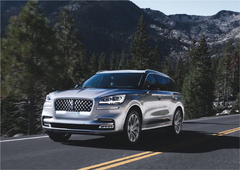 A 2023 Lincoln Aviator® Grand Touring SUV being driven on a winding road to demonstrate the capabilities of all-wheel drive | Buss Lincoln in McHenry IL
