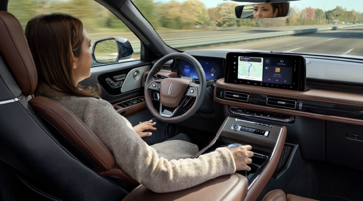 A woman is seen sitting in the driver’s seat of her 2025 Lincoln Aviator® SUV with her hands off the steering wheel. | Buss Lincoln in McHenry IL