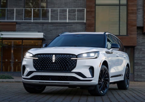 A 2026 Lincoln Aviator® Reserve model is shown with the available Jet Appearance Package parked near a restaurant. | Buss Lincoln in McHenry IL