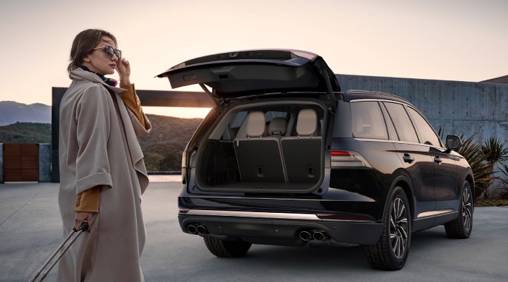 A woman approaches a 2026 Lincoln Aviator® SUV with its rear liftgate open. | Buss Lincoln in McHenry IL