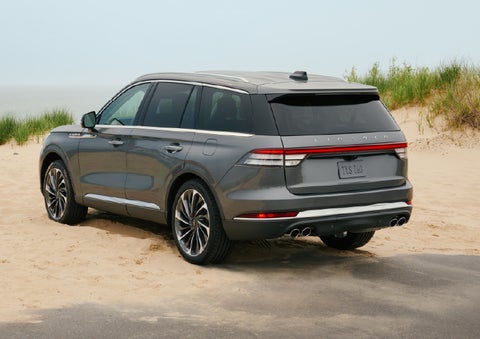 A 2027 Lincoln Aviator® SUV is parked next to sand dunes. | Buss Lincoln in McHenry IL