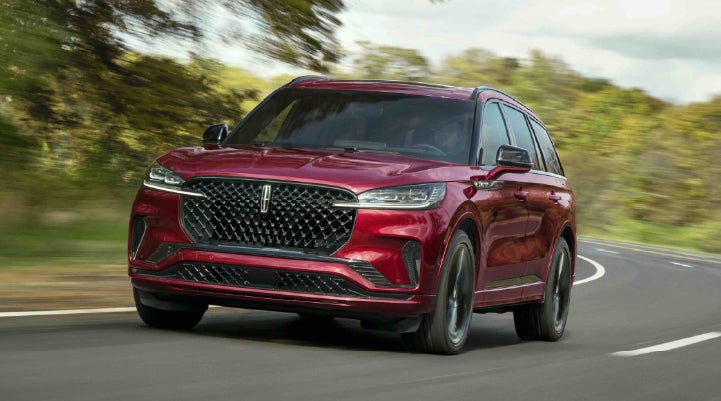 A 2027 Lincoln Aviator® SUV is being driven on a country road | Buss Lincoln in McHenry IL