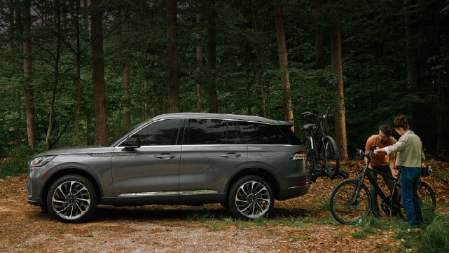 A father and son load e-bikes on a bike rack attached to a 2027 Lincoln Aviator® SUV. | Buss Lincoln in McHenry IL