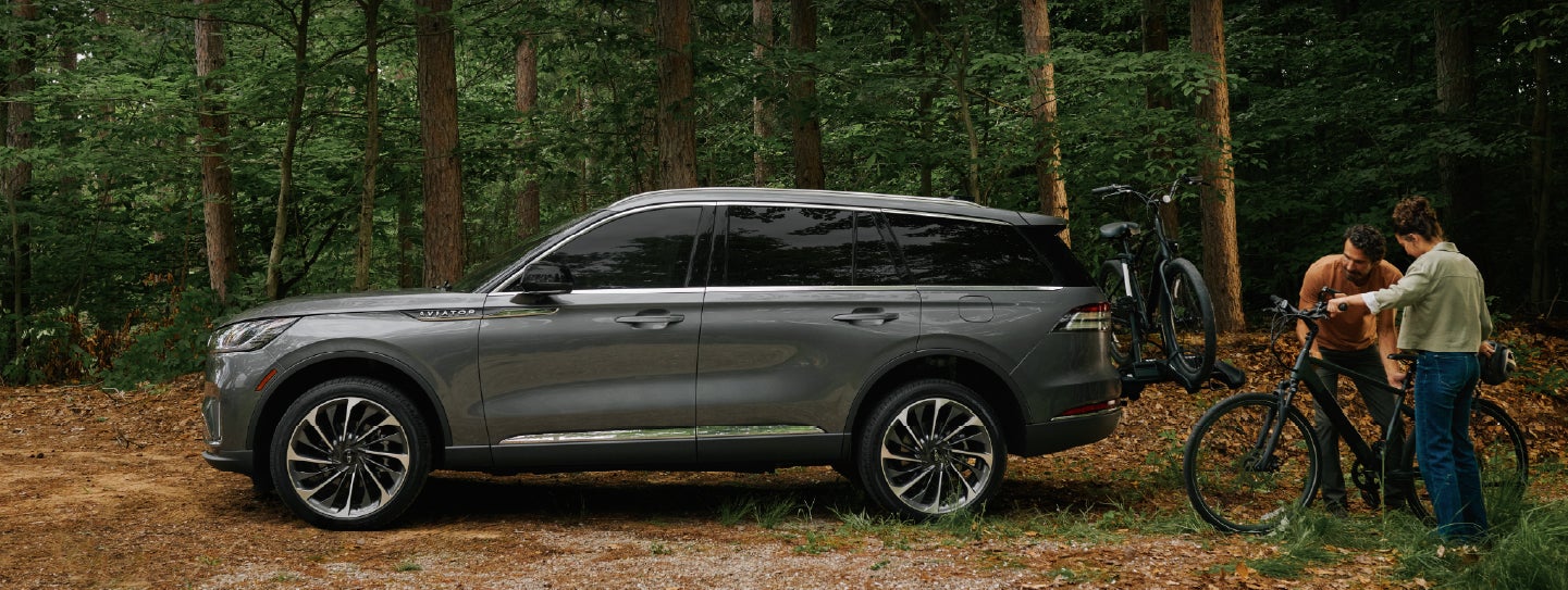 A father and son load e-bikes on a bike rack attached to a 2027 Lincoln Aviator® SUV. | Buss Lincoln in McHenry IL